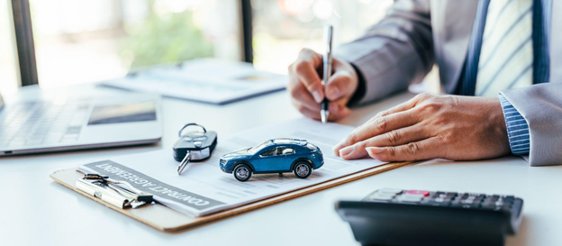A hand signing papers next to a car