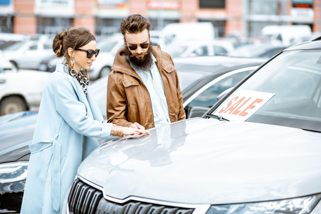 A man and a woman touching a "for sale" car